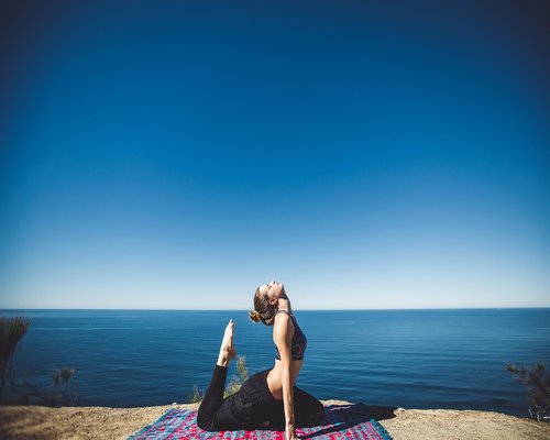 Woman drinking water and practicing light yoga stretches comfortably in a sunlit room